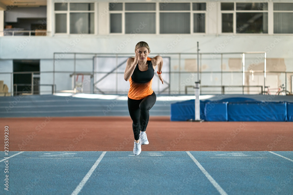 Athletic blonde woman training at indoor stadium Athletic blonde woman training at indoor stadium