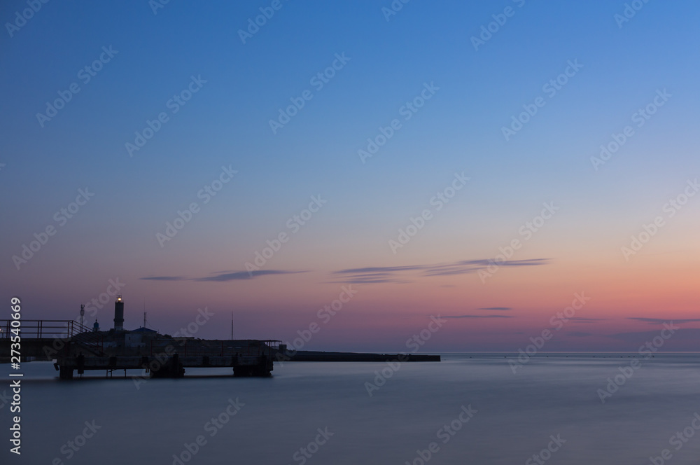 Long exposure. Silhouette of the pier and lighthouse at sunset