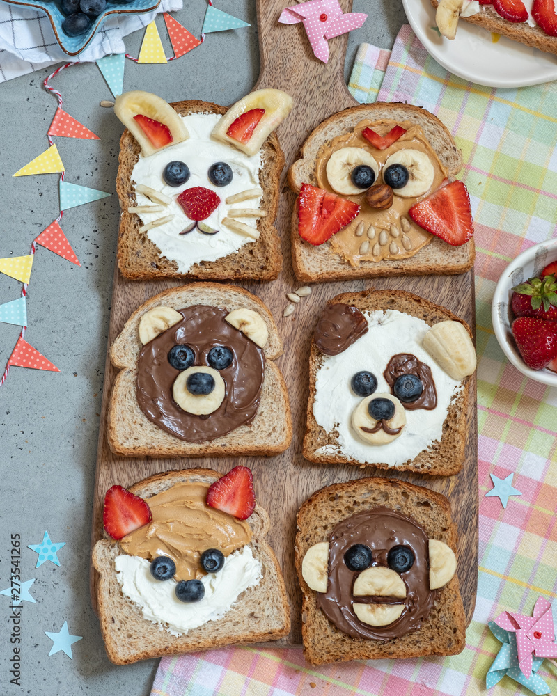 Funny animal faces toasts with spreads, banana, strawberry and blueberry