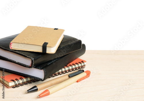 Notebooks and pens on woode...