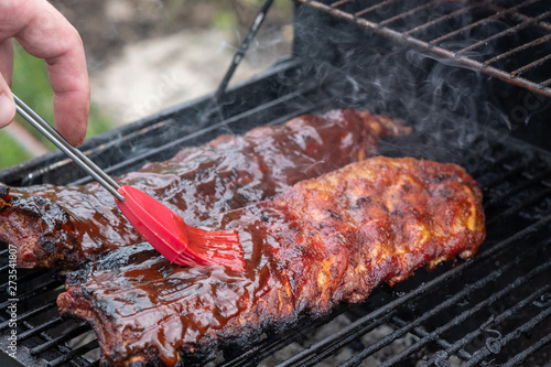 Фотография Pork ribs cooking on barbecue grill for summer outdoor party.