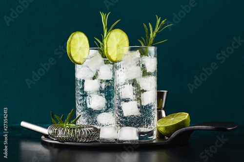 Quadro su tela classic gin and tonic cocktail with rosemary sprigs in tall glasses on a table w