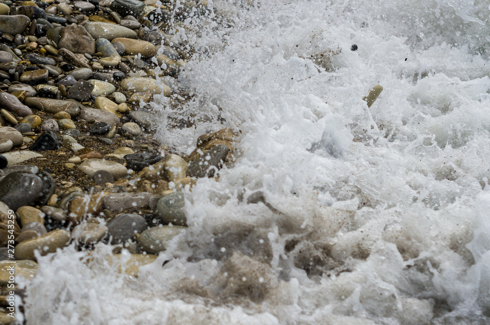 Obraz premium pebble stones on the sea beach, the rolling waves of the sea with foam