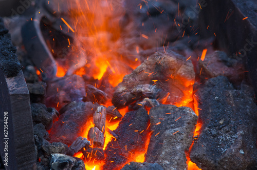 blacksmith furnace with burning coals, tools, and glowing hot metal workpieces