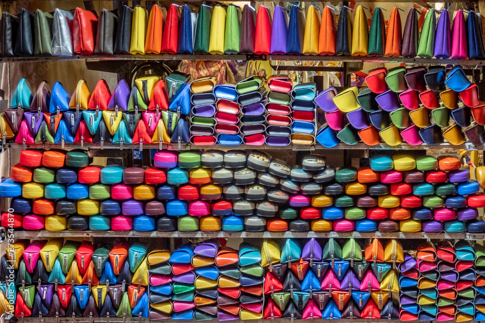 Colorful leather purses, handbags, wallets and handbags are displayed by street vendors at an outdoor Market, in Florence, Italy.