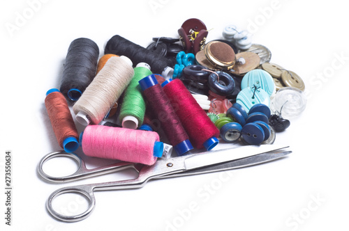 Colored spools of thread, buttons and scissors are a bunch on white background