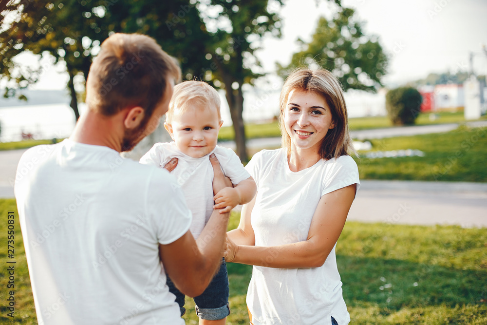 Family in a summer park. Mother in a white t-shirt. Cute little boy with a dad Family in a summer park. Mother in a white t-shirt. Cute little boy with a dad