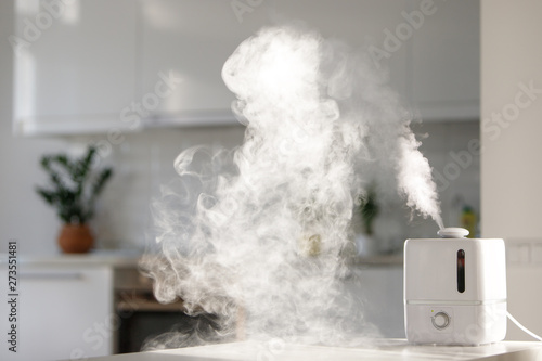 Fotografi Aroma oil diffuser on the table at home, steam from the air humidifier