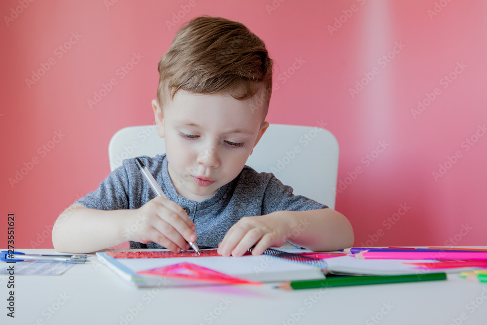 Portrait of cute kid boy at home making homework. Little concentrated child writing with colorful pencil, indoors. Elementary school and education. Kid learning writing letters and numbers Portrait of cute kid boy at home making homework. Little concentrated child writing with colorful pencil, indoors. Elementary school and education. Kid learning writing letters and numbers
