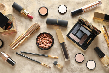 Different luxury makeup products on gold background, flat lay