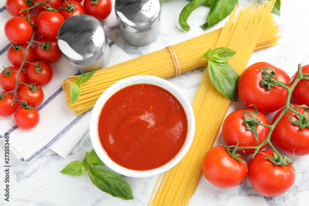 Flat lay composition with bowl of sauce, pasta and tomatoes on marble table Flat lay composition with bowl of sauce, pasta and tomatoes on marble table