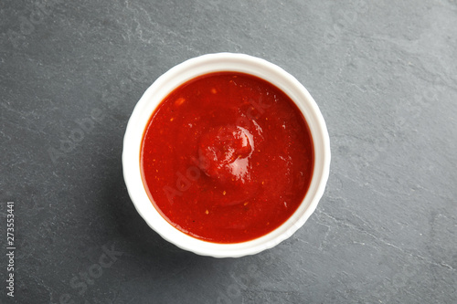 Bowl of tasty tomato sauce on grey table, top view