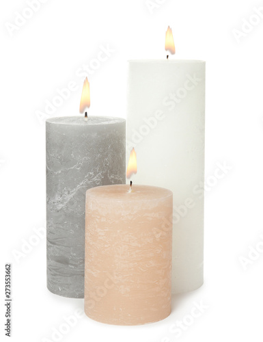 Three alight wax candles on white background
