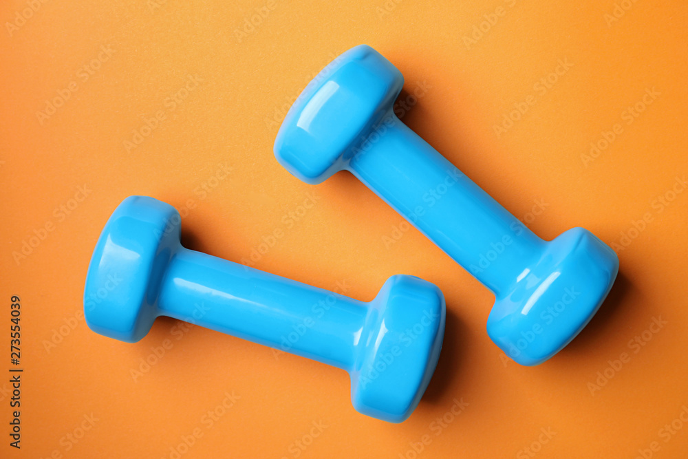 Bright dumbbells on color background, flat lay. Home fitness Bright dumbbells on color background, flat lay. Home fitness