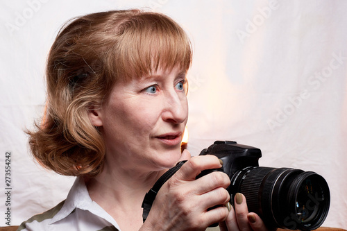 Blonde-haired female photographer with photo camera in her hands on a white background