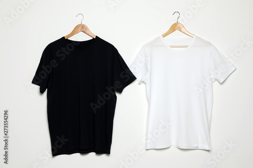 Hangers with blank t-shirts on white background. Mock up for design