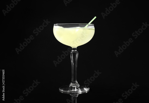 Glass of delicious cucumber martini with ice on dark background