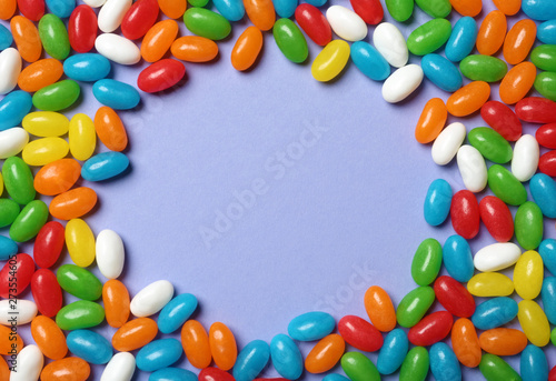 Frame made of bright jelly candies on color background, flat lay. Space for text