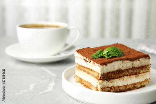 Tiramisu cake with cup on table against light background  space for text