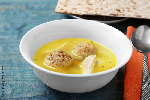 Bowl of Jewish matzoh balls soup on color wooden table