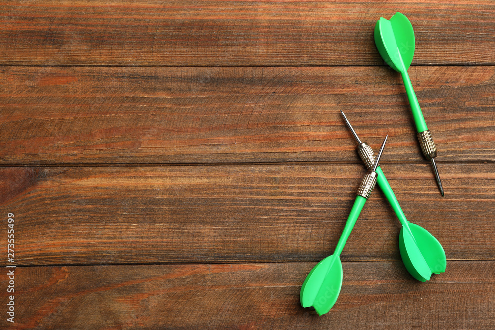 Dart arrows on wooden background, flat lay. Space for text Dart arrows on wooden background, flat lay. Space for text