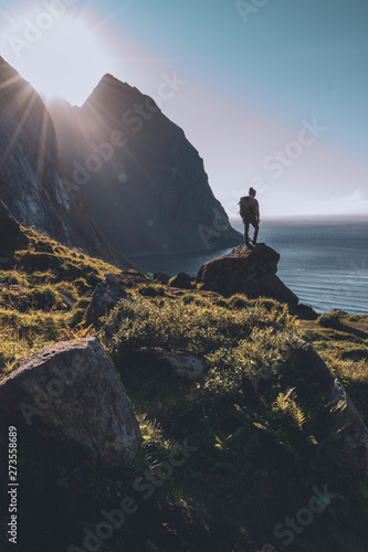 Man mountaineer standing on rock of peak mountain at sunset. Ryten Mountain, Norway