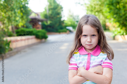 Upset or offended little girl 5 years standing on street near home. Escape from the house. Relation problems concept.