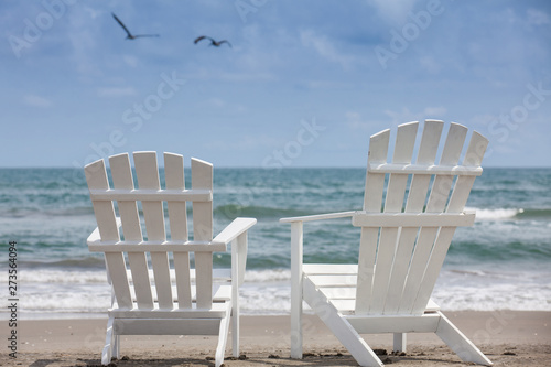 Empty white wooden chairs at a paradisiac beach on the tropics in a beautiful sunny day