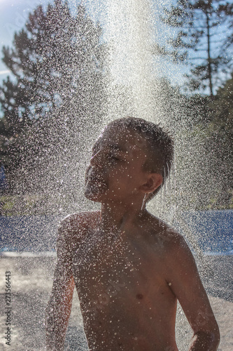 Close-up photo of a boy under the shower near the swimming pool.