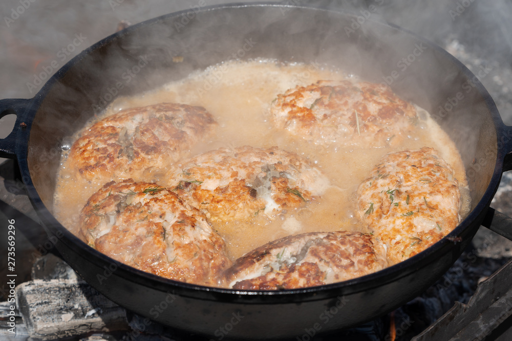 Delicious wild red salmon fish cutlet with gravy fried in hot griddle roast on coals, over open fire on campfire. Cooking food on fire during picnic on sunny summer weather. Delicious wild red salmon fish cutlet with gravy fried in hot griddle roast on coals, over open fire on campfire. Cooking food on fire during picnic on sunny summer weather.