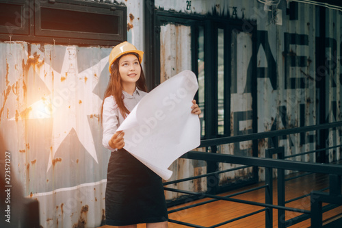 young engineers wearing helmat looking up holding blueprint modern project in the office, Engineer concept photo