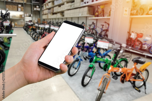 businessman holding blank screen for text on smartphone, mobile, cell phone with blurry bicycle shop background.