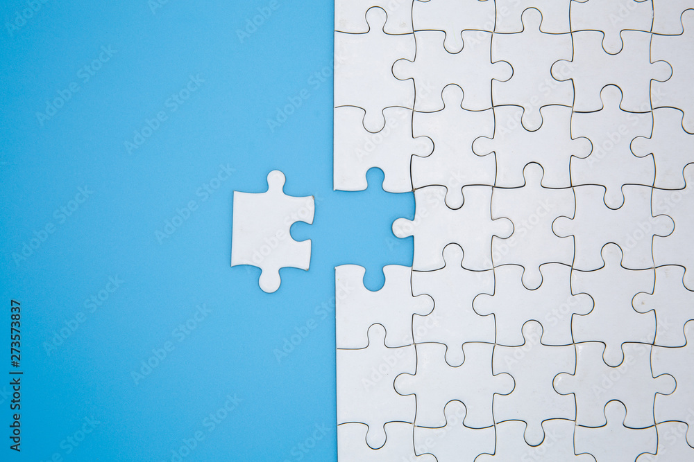 Unfinished white jigsaw puzzle pieces on blue background, The last piece of jigsaw puzzle, Copy space. Unfinished white jigsaw puzzle pieces on blue background, The last piece of jigsaw puzzle, Copy space.