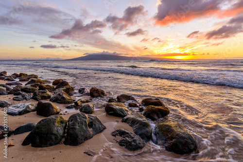 Fototapeta Naklejka Na Ścianę i Meble -  Tropical Sunset - A colorful sunset at a rocky beach of north-west coast of Maui island, with Lanai island at horizon. Hawaii, USA.