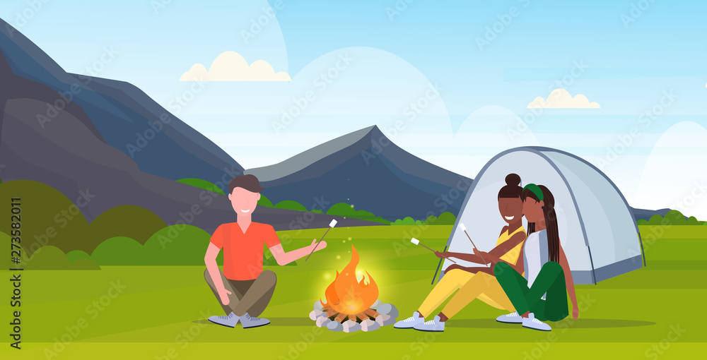 people hikers roasting marshmallow candies on campfire hiking camping concept mix race man women travelers on hike mountains nature landscape horizontal full length flat
