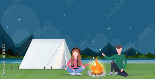 couple hikers roasting marshmallow candies on campfire hiking camping concept man women travelers on hike night mountains landscape nature background horizontal full length flat