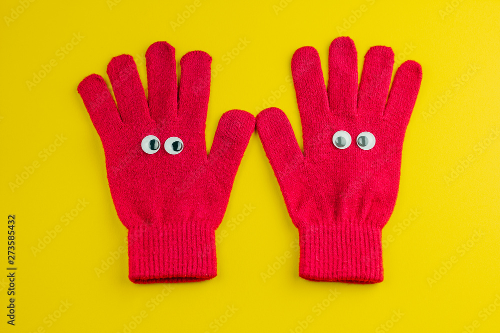 top view flat lay two gloves with eyes on a yellow background top view flat lay two gloves with eyes on a yellow background