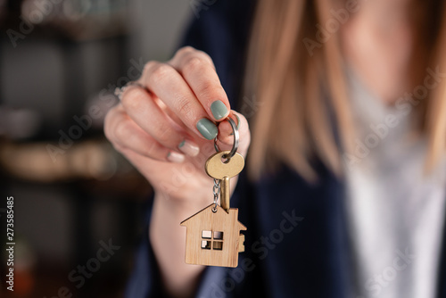 Concept of renting an apartment. House key in womans hands. Young woman. Modern light lobby interior. Real estate, hypothec, moving home or renting property.