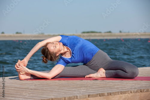 Woman making yoga exercise at a lake © biggur