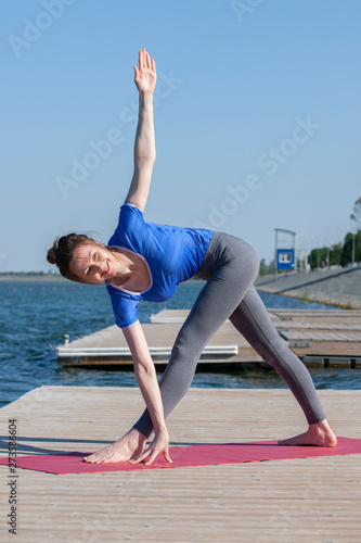 Woman making yoga exercise at a lake