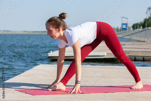 Healthy lifestyle in nature,Woman doing yoga exercise on mat in park near lake.