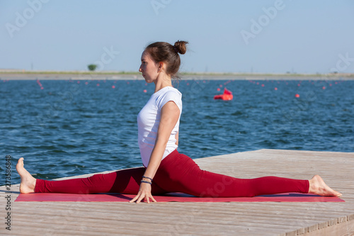 Young girl practices yoga on the shore of the lake, the concept of enjoying privacy and concentration, sunlight