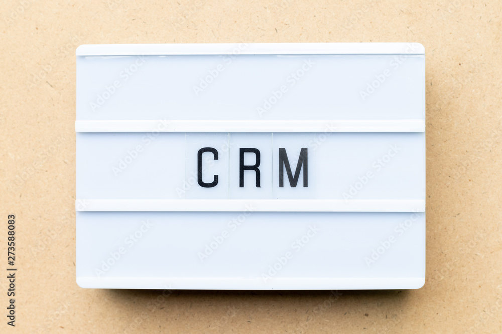White lightbox with word CRM (Abbreviation of Customer Relationship Management) on wood background White lightbox with word CRM (Abbreviation of Customer Relationship Management) on wood background