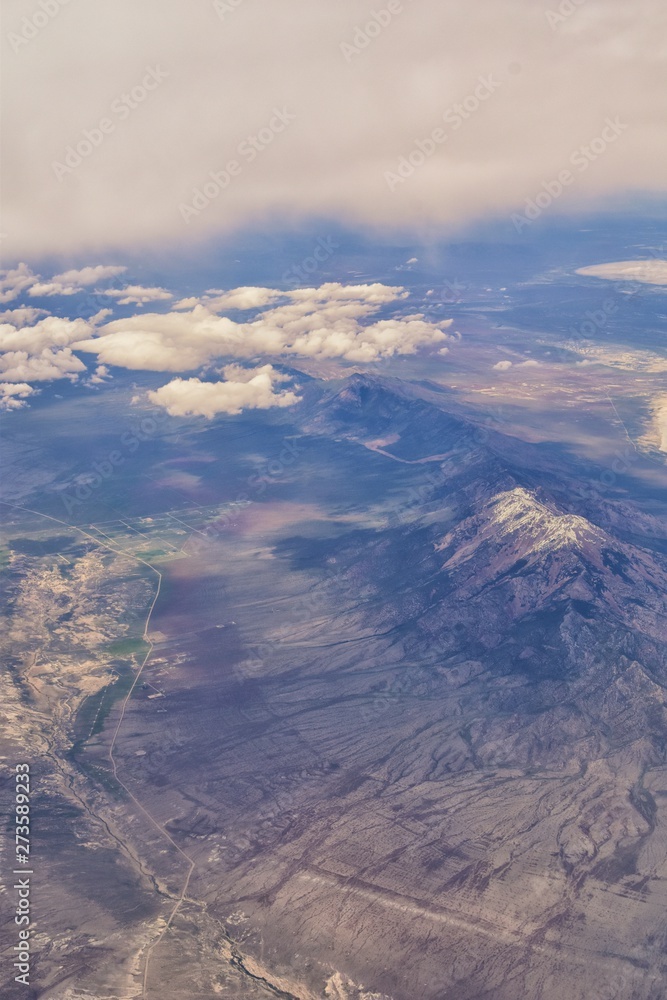 Aerial view from airplane of the Great Salt Lake in Rocky Mountain Range, sweeping cloudscape and landscape during day time in Spring. In Utah, United States.