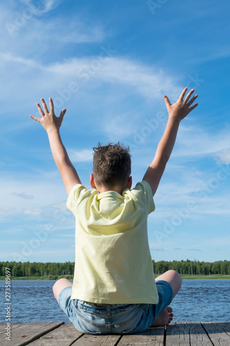 boy doing yoga in nature by the lake on a nice sunny day