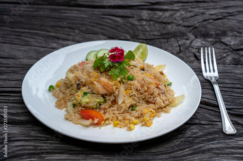 Fried rice with shrimps and vegetables in a white dish on an old wooden table, close up . Thai food , Thai cuisine