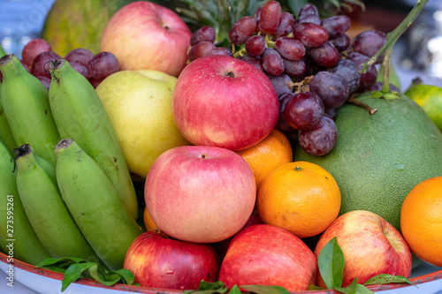 Assortment of fresh fruit banana  grapes  orange  apple  pineapple  tangerine and grapefruit on a tray. Closeup