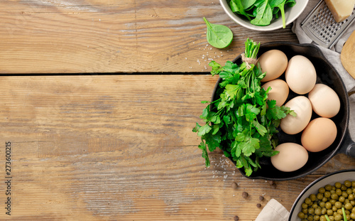 Healthy breakfast table with ingredient for cooking. peas, eggs, spinach, parsley and cheese on wooden background top view copy space