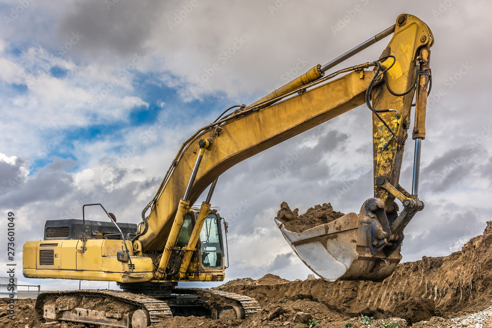 An excavator extracting dirt in a construction site An excavator extracting dirt in a construction site