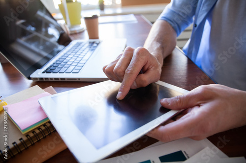 close up hands of man touching tablet, multitasking on screen in an office.